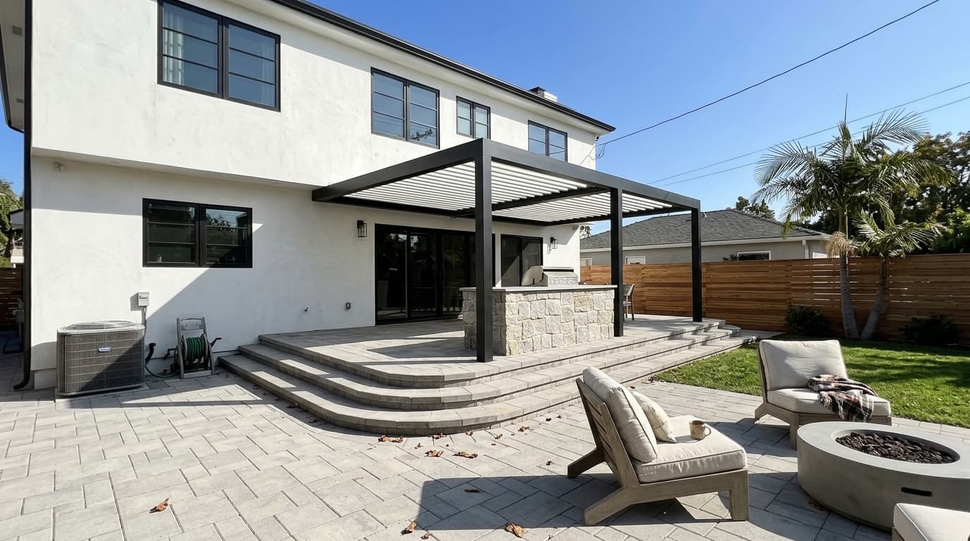 Backyard patio with a black louvered pergola, a stone outdoor kitchen, wide curved steps and a fire pit